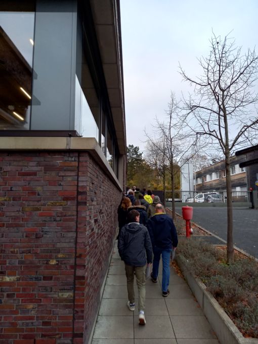 Mehrere Personen die einen Weg an einem Haus entlanglaufen.